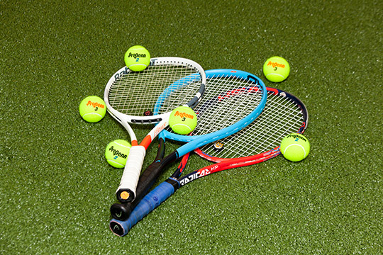 tennis racquets and tennis balls on green turf floor